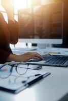 Cropped image of professional businesswoman working at her office via laptop, young female manager using portable computer device while sitting at modern loft, flare light, work process concept photo