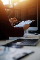 Cropped image of professional businesswoman working at her office via laptop, young female manager using portable computer device while sitting at modern loft, flare light, work process concept photo