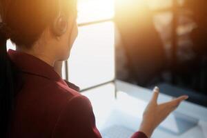 Friendly female helpline operator in call center. Young woman working in call center and holding microphone on headset with hand. photo