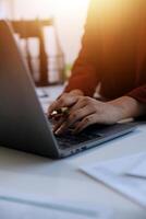 Cropped image of professional businesswoman working at her office via laptop, young female manager using portable computer device while sitting at modern loft, flare light, work process concept photo