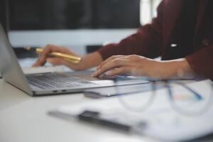 Cropped image of professional businesswoman working at her office via laptop, young female manager using portable computer device while sitting at modern loft, flare light, work process concept photo