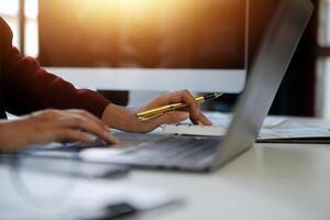 Cropped image of professional businesswoman working at her office via laptop, young female manager using portable computer device while sitting at modern loft, flare light, work process concept photo