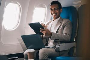 Airplane, travel and portrait of businessman working on laptop computer and smartphone while sitting in airplane. photo