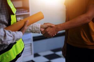 Architect men making handshake in construction site. Employee or worker shake hands to employer man for greeting, dealing, teamwork, collaboration some project or business. They are good team photo