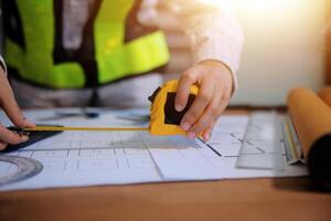 engineer people meeting working and pointing at a blueprint in office for discussing. Engineering tools and construction concept photo