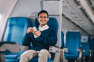 Man with dark hair is reading text message on mobile phone and speaking by phone during flying in the airplane photo