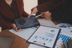 Group of confident business people point to graphs and charts to analyze market data, balance sheet, account, net profit to plan new sales strategies to increase production capacity. photo