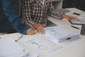 Group of confident business people point to graphs and charts to analyze market data, balance sheet, account, net profit to plan new sales strategies to increase production capacity. photo
