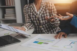 Group of confident business people point to graphs and charts to analyze market data, balance sheet, account, net profit to plan new sales strategies to increase production capacity. photo
