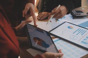 Group of confident business people point to graphs and charts to analyze market data, balance sheet, account, net profit to plan new sales strategies to increase production capacity. photo