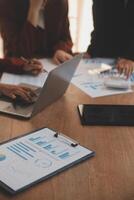 Group of confident business people point to graphs and charts to analyze market data, balance sheet, account, net profit to plan new sales strategies to increase production capacity. photo