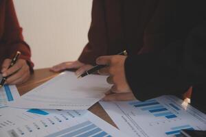 Group of confident business people point to graphs and charts to analyze market data, balance sheet, account, net profit to plan new sales strategies to increase production capacity. photo