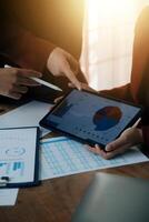 Group of confident business people point to graphs and charts to analyze market data, balance sheet, account, net profit to plan new sales strategies to increase production capacity. photo