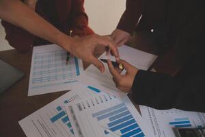 Group of confident business people point to graphs and charts to analyze market data, balance sheet, account, net profit to plan new sales strategies to increase production capacity. photo