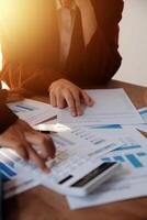 Group of confident business people point to graphs and charts to analyze market data, balance sheet, account, net profit to plan new sales strategies to increase production capacity. photo