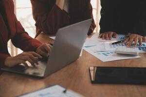 Group of confident business people point to graphs and charts to analyze market data, balance sheet, account, net profit to plan new sales strategies to increase production capacity. photo