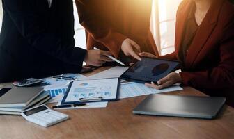Group of confident business people point to graphs and charts to analyze market data, balance sheet, account, net profit to plan new sales strategies to increase production capacity. photo