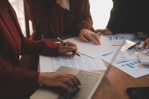 Group of confident business people point to graphs and charts to analyze market data, balance sheet, account, net profit to plan new sales strategies to increase production capacity. photo