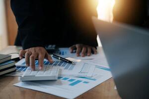 Group of confident business people point to graphs and charts to analyze market data, balance sheet, account, net profit to plan new sales strategies to increase production capacity. photo