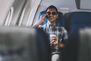 Traveling and technology. happy young businessman working on laptop computer and smartphone while sitting in airplane. photo