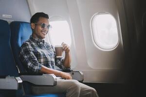 Asian man enjoying enjoys a coffee comfortable flight while sitting in the airplane cabin, Passengers near the window. photo