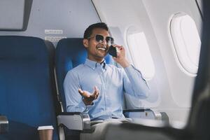 Traveling and technology. happy young businessman working on laptop computer and smartphone while sitting in airplane. photo
