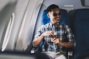 Asian man enjoying enjoys a coffee comfortable flight while sitting in the airplane cabin, Passengers near the window. photo