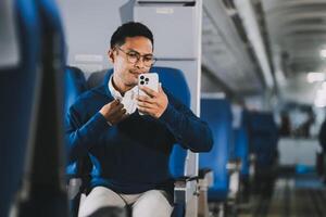 Man with dark hair is reading text message on mobile phone and speaking by phone during flying in the airplane photo