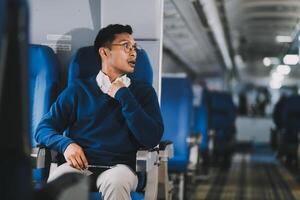 Man with dark hair is reading text message on mobile phone and speaking by phone during flying in the airplane photo