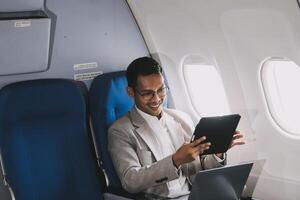 Airplane, travel and portrait of businessman working on laptop computer and smartphone while sitting in airplane. photo