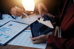 Group of confident business people point to graphs and charts to analyze market data, balance sheet, account, net profit to plan new sales strategies to increase production capacity. photo