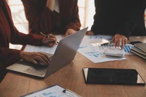 Group of confident business people point to graphs and charts to analyze market data, balance sheet, account, net profit to plan new sales strategies to increase production capacity. photo