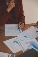 Group of confident business people point to graphs and charts to analyze market data, balance sheet, account, net profit to plan new sales strategies to increase production capacity. photo