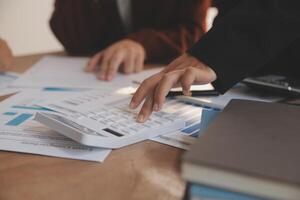 Group of confident business people point to graphs and charts to analyze market data, balance sheet, account, net profit to plan new sales strategies to increase production capacity. photo
