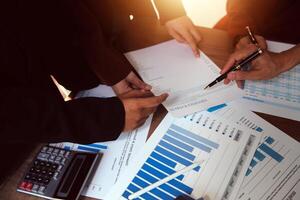Group of confident business people point to graphs and charts to analyze market data, balance sheet, account, net profit to plan new sales strategies to increase production capacity. photo