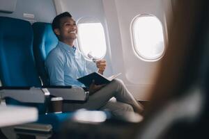 Airplane, travel and portrait of businessman working on laptop computer and smartphone while sitting in airplane. photo