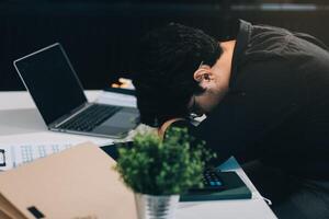 Frustrated Asian young businessman worker working on table in office. Busy employee worker people feel tired and headache from late work and overwork job document on computer desk at company workplace photo