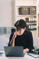 Frustrated Asian young businessman worker working on table in office. Busy employee worker people feel tired and headache from late work and overwork job document on computer desk at company workplace photo