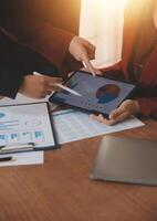 Group of confident business people point to graphs and charts to analyze market data, balance sheet, account, net profit to plan new sales strategies to increase production capacity. photo
