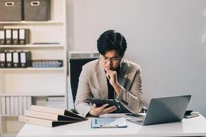 Frustrated Asian young businessman worker working on table in office. Busy employee worker people feel tired and headache from late work and overwork job document on computer desk at company workplace photo
