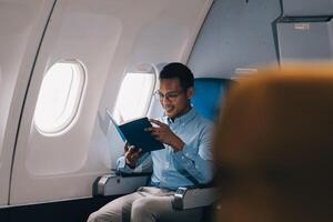 Airplane, travel and portrait of businessman working on laptop computer and smartphone while sitting in airplane. photo