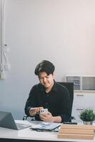 Happy smiling businessman wearing casual clothes and using modern smartphone in his home office during the day, typing, touching the screen, browsing the internet or writing text messages. photo