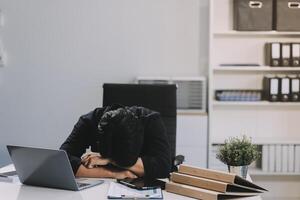 Frustrated Asian young businessman worker working on table in office. Busy employee worker people feel tired and headache from late work and overwork job document on computer desk at company workplace photo