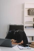 Frustrated Asian young businessman worker working on table in office. Busy employee worker people feel tired and headache from late work and overwork job document on computer desk at company workplace photo