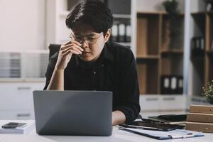 Frustrated Asian young businessman worker working on table in office. Busy employee worker people feel tired and headache from late work and overwork job document on computer desk at company workplace photo