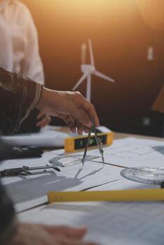 Team of multiethnic architects working on construction plans in meeting room. Engineers discussing on project in office. Mature businessman and woman standing around table working on blueprint. photo