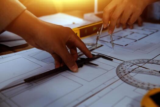 Team of multiethnic architects working on construction plans in meeting room. Engineers discussing on project in office. Mature businessman and woman standing around table working on blueprint. photo