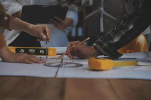 Team of multiethnic architects working on construction plans in meeting room. Engineers discussing on project in office. Mature businessman and woman standing around table working on blueprint. photo