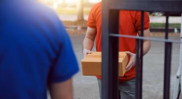 Asian delivery express courier young man use giving boxes to woman customer he wearing protective face mask at front home photo