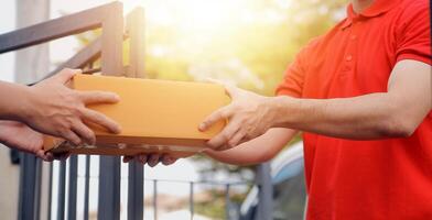 Asian delivery express courier young man use giving boxes to woman customer he wearing protective face mask at front home photo